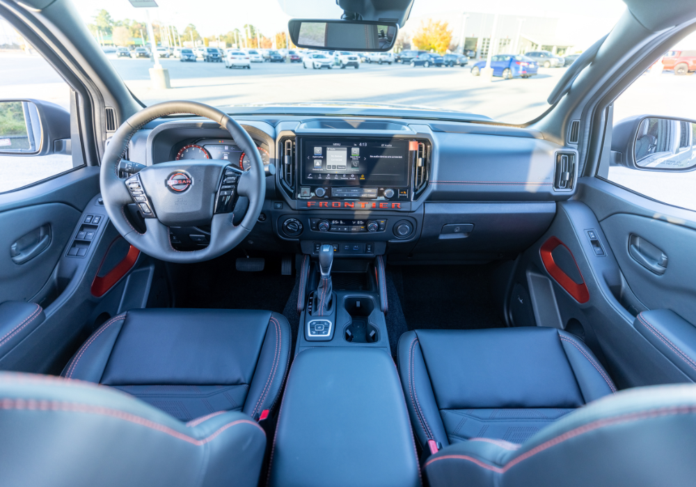 Nissan Frontier interior showing the entire front dash. The seats are black with orange stitching